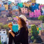 A responsible digital nomad holding a cup of coffee in front of a colorful village