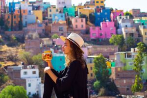 A responsible digital nomad holding a cup of coffee in front of a colorful village