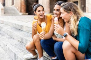 three women friends with ice cream cones laughing together to live longer