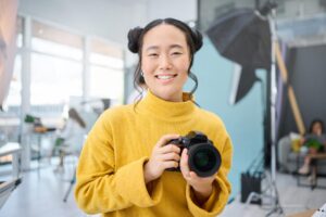 find a job you love like this smiling woman holding a camera in a photography studio
