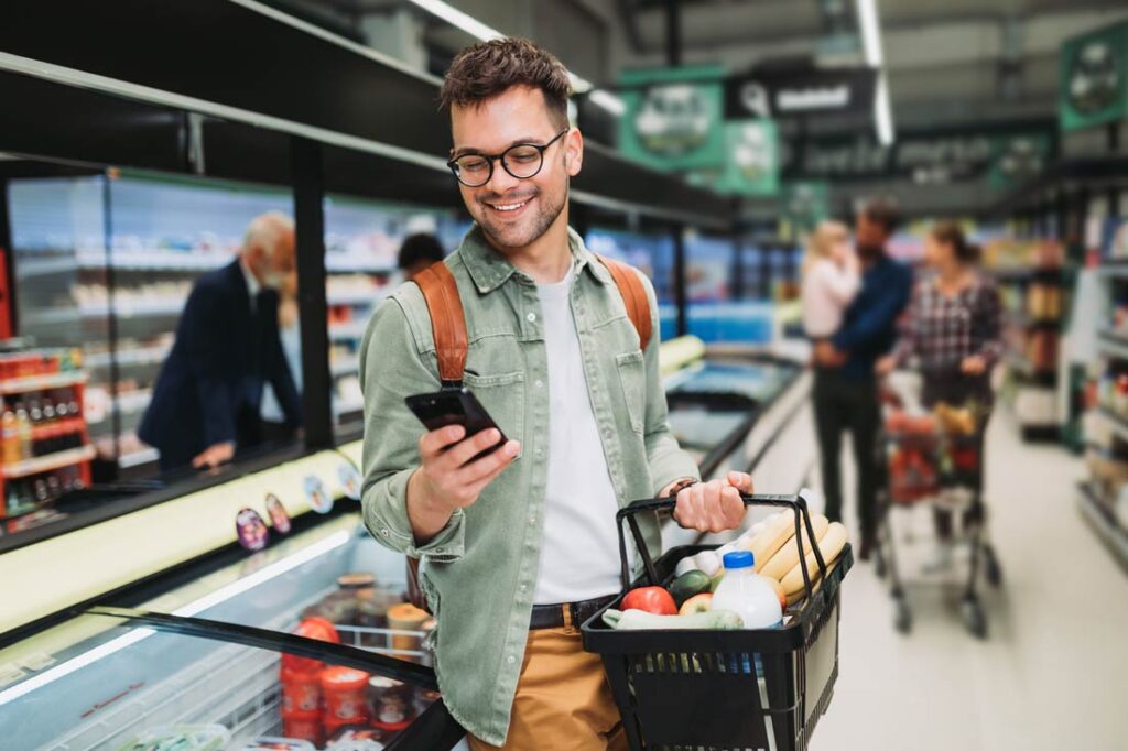 man saving money on groceries by comparing prices on phone