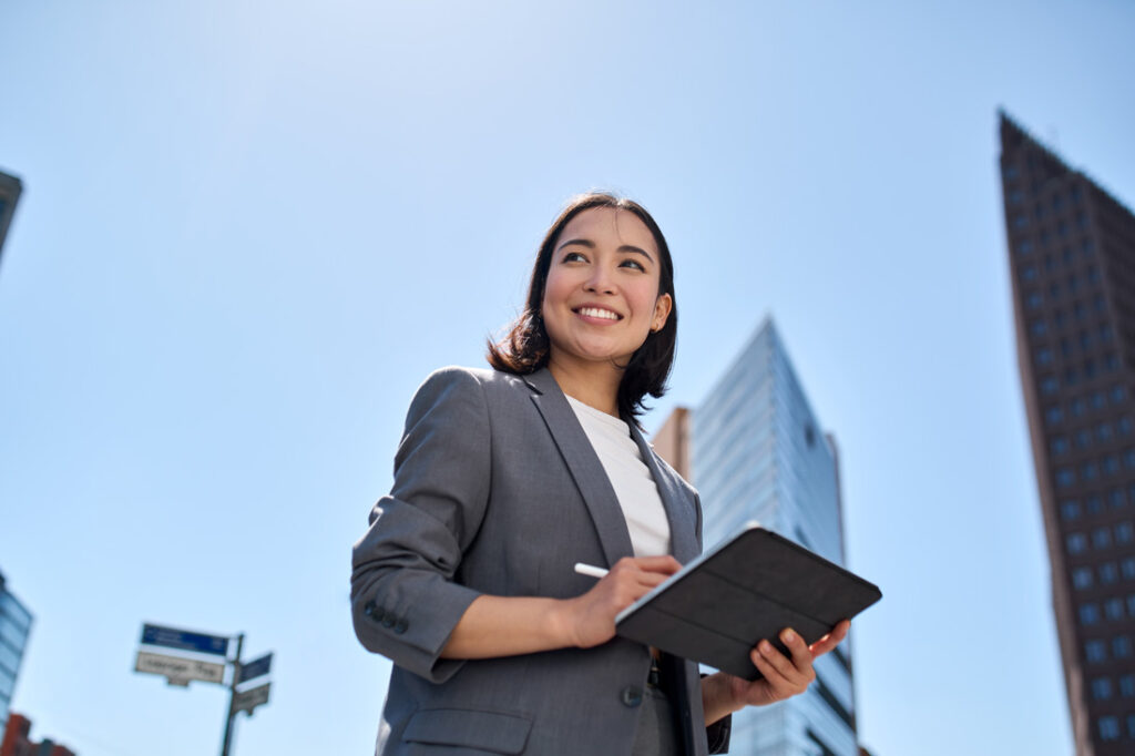 Young Asian business woman planning her time management strategies on a tablet outside in the city