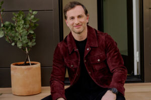 Airbnb co-founder Joe Gebbia sitting on a doorstep smiling at the camera