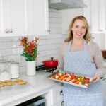 The Real Good Life founder Maggie Skarich Joos pictured holding a platter of food in her kitchen