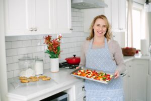 The Real Good Life founder Maggie Skarich Joos pictured holding a platter of food in her kitchen