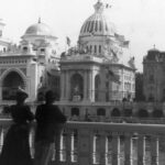 a man and woman look out over a view of Paris during the exposition featuring US manufacturers
