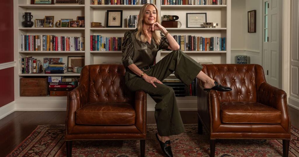 Kris Carr posing in front of her home library bookshelf