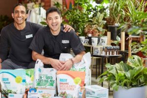 The founders of Back to the Roots smiling among plants and their brand's products