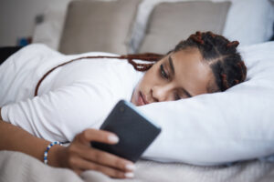 girl laying her head on a pillow and logging into Innerworld on her phone