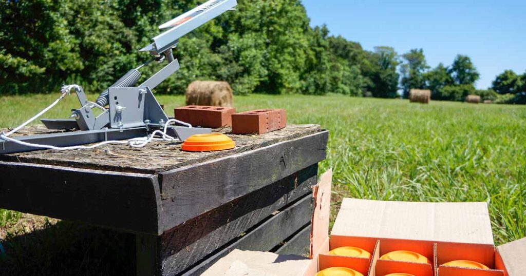 skeet thrower and box of targets on a grassy field