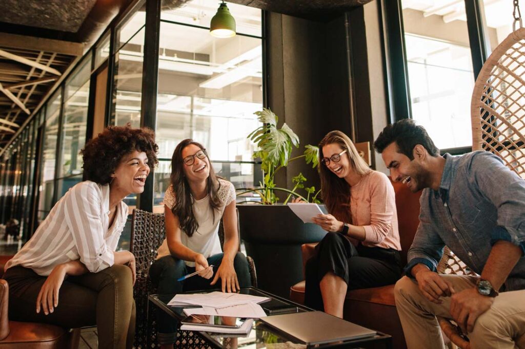 Photograph of 4 people working together and smiling to represent the components of emotional intelligence