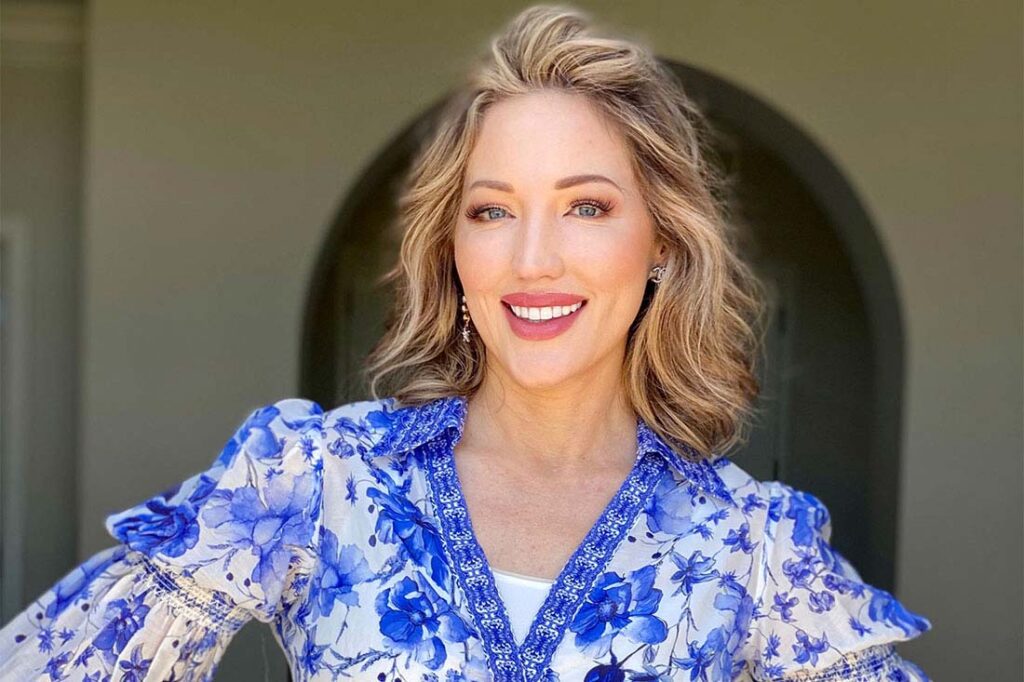 Debbie Biery, a white woman with shoulder length blond hair, red lipstick, and a blue floral shirt, smiling to represent her CEO mindset