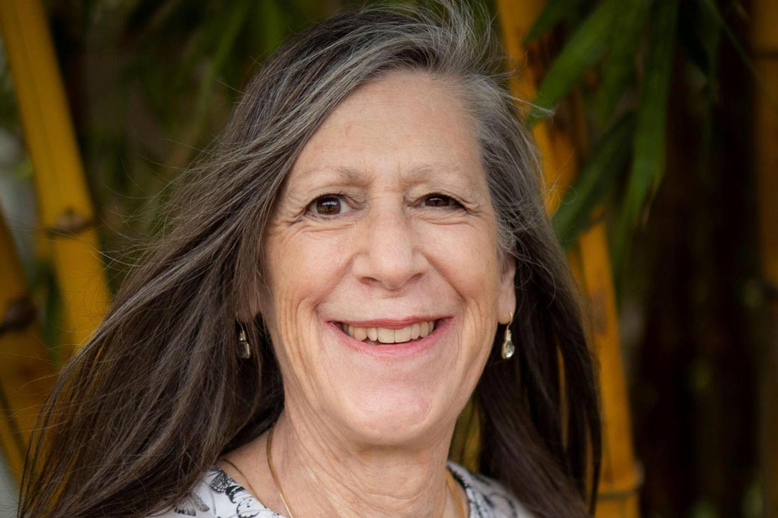 Mature white woman, Linda Wilson, coach, mentor and speaker, with long grey hair smiling