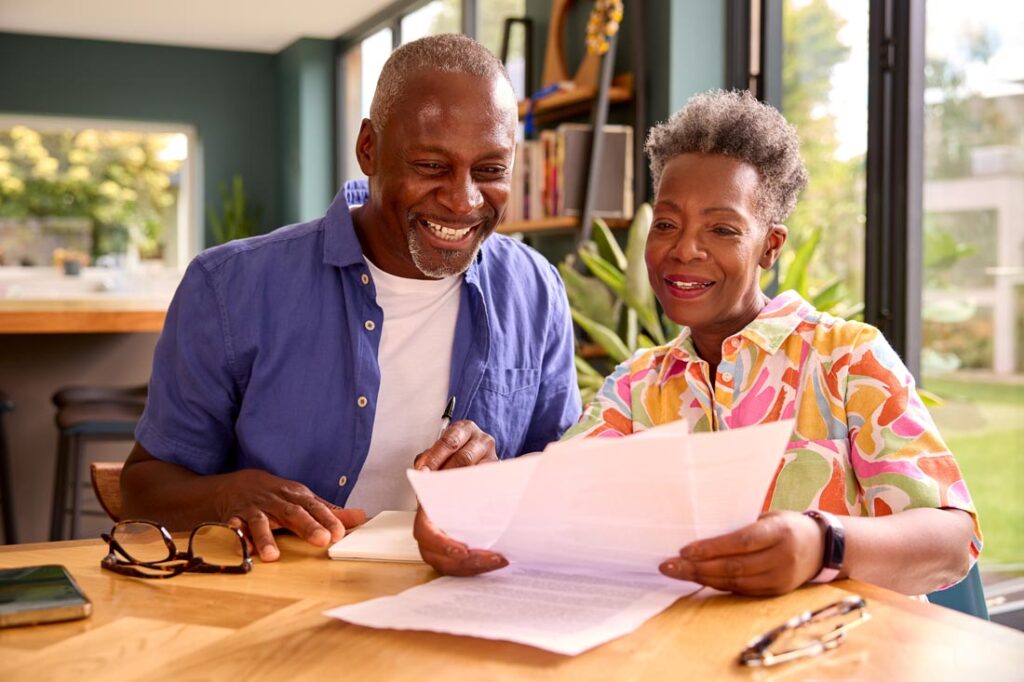 Older Black couple smiling and looking at paperwork