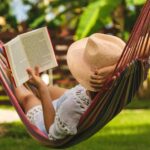 woman reading a book on a hammock after she learned how to truly take time off work