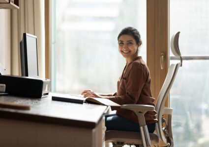 An Indian woman smiling and working at her ergonomic home office