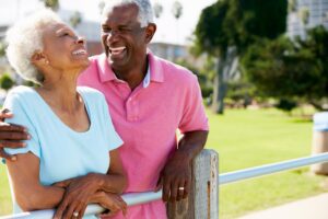 Photograph of a mature Black couple laughing outside to represent life insurance retirement plan
