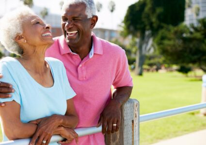 Photograph of a mature Black couple laughing outside to represent life insurance retirement plan