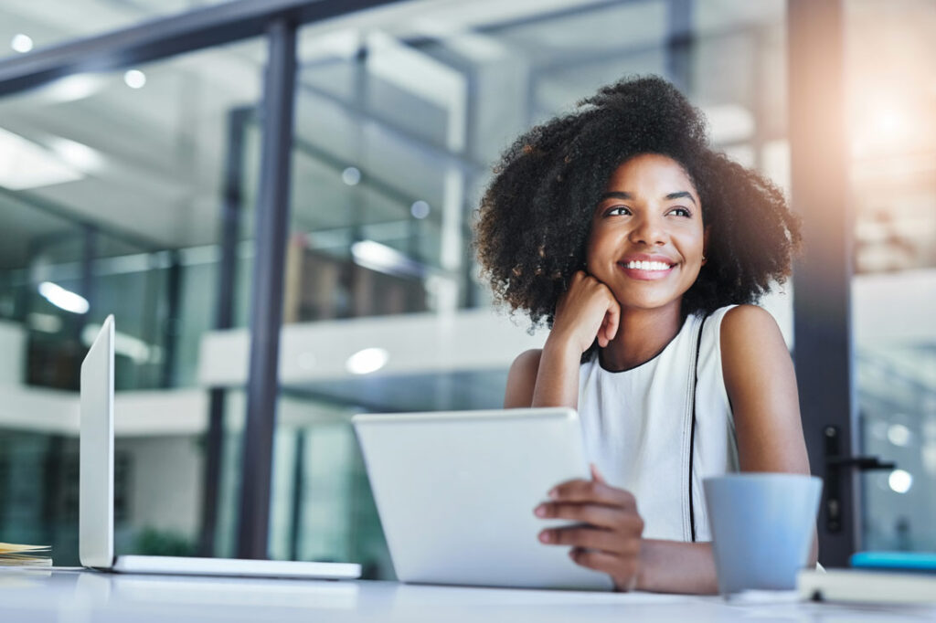 Young Black woman doing a personal development course and smiling in business attire.