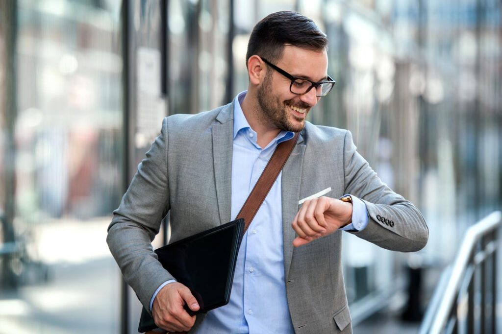 Businessman walking in the city and looking at his watch because he understands the importance of time management