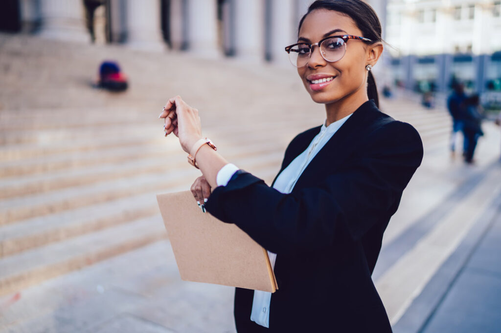 Business woman checking her watch and her time management apps