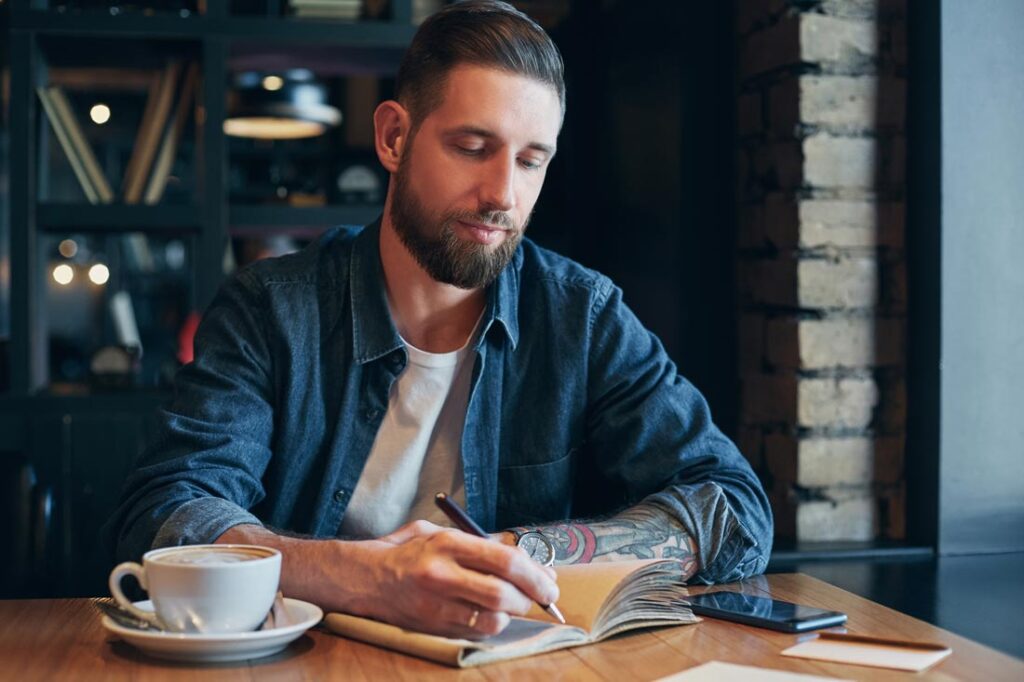 man writing in journal to boost his personal development
