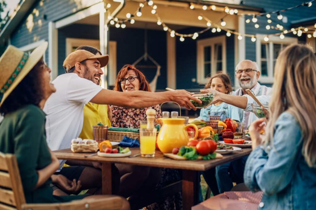 Multigenerational family sitting outside eating a healthy meal together showing what its like to live to 100 secrets of the blue zones