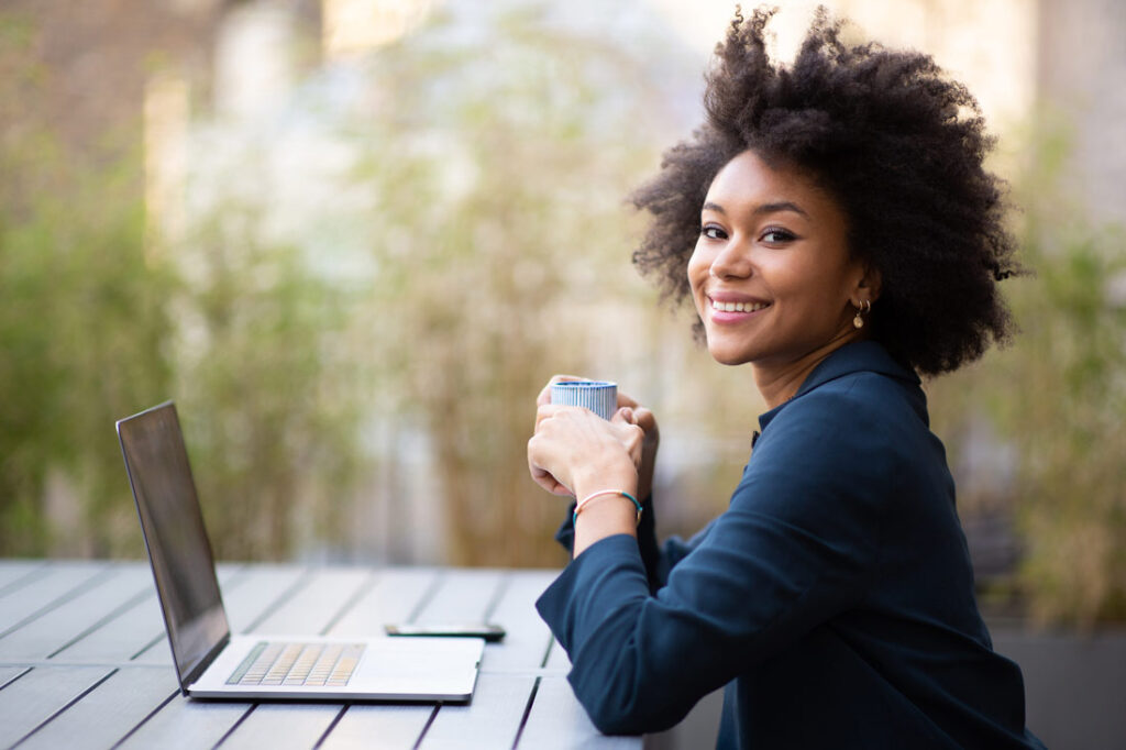 Black woman working outside on her personal development plan and drinking coffee