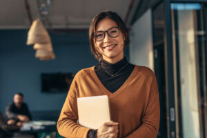 Asian business woman smiling holding tablet where she does soft skills training courses