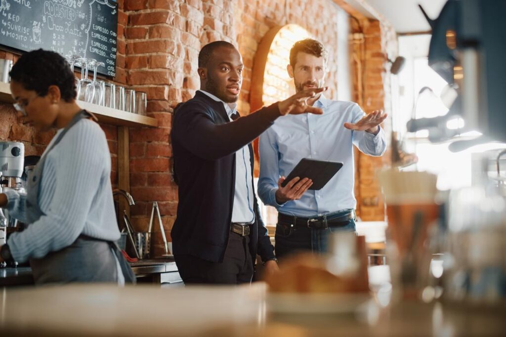 Two business owners in a cafe sharing responsibilities with a total responsibility transfer