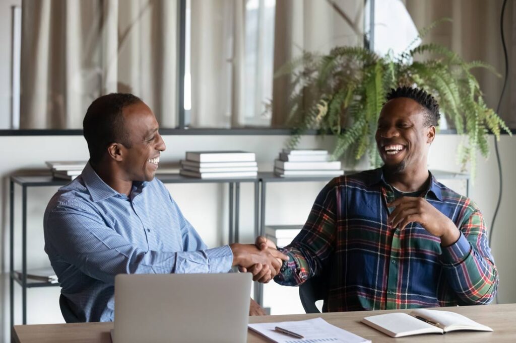 Two Black businessmen shaking on a merger and a acquisition in a nice office