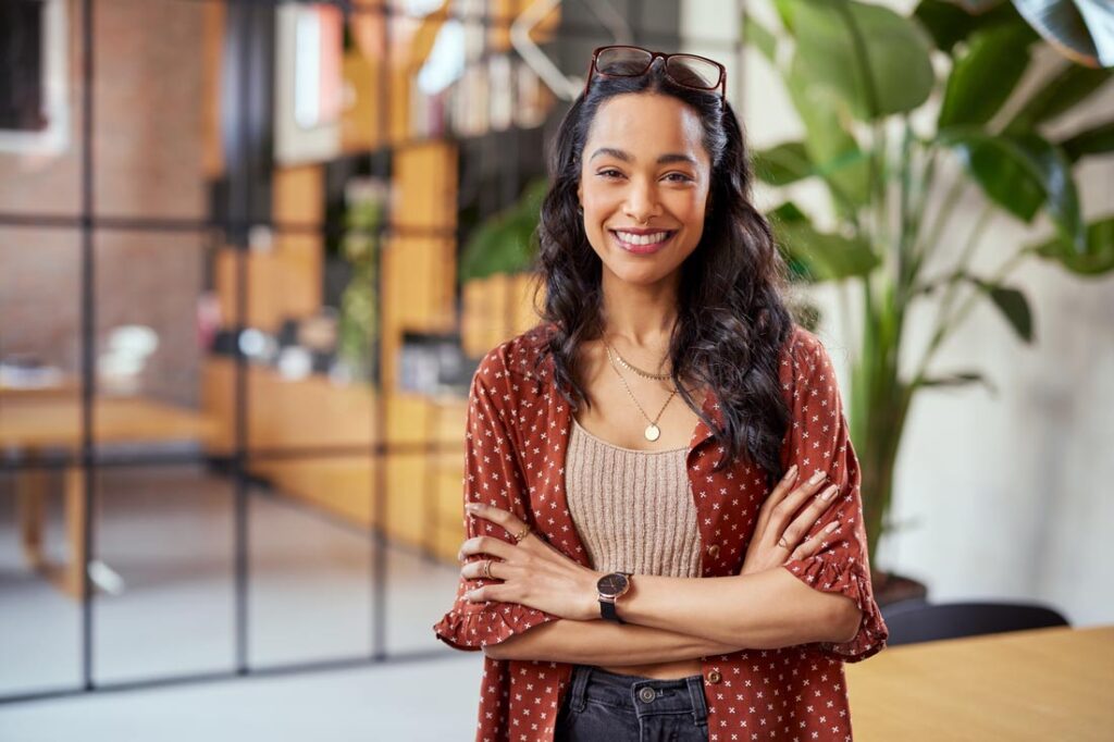 Business woman standing in front of her store, arms crossed, ready to learn about soft skills examples