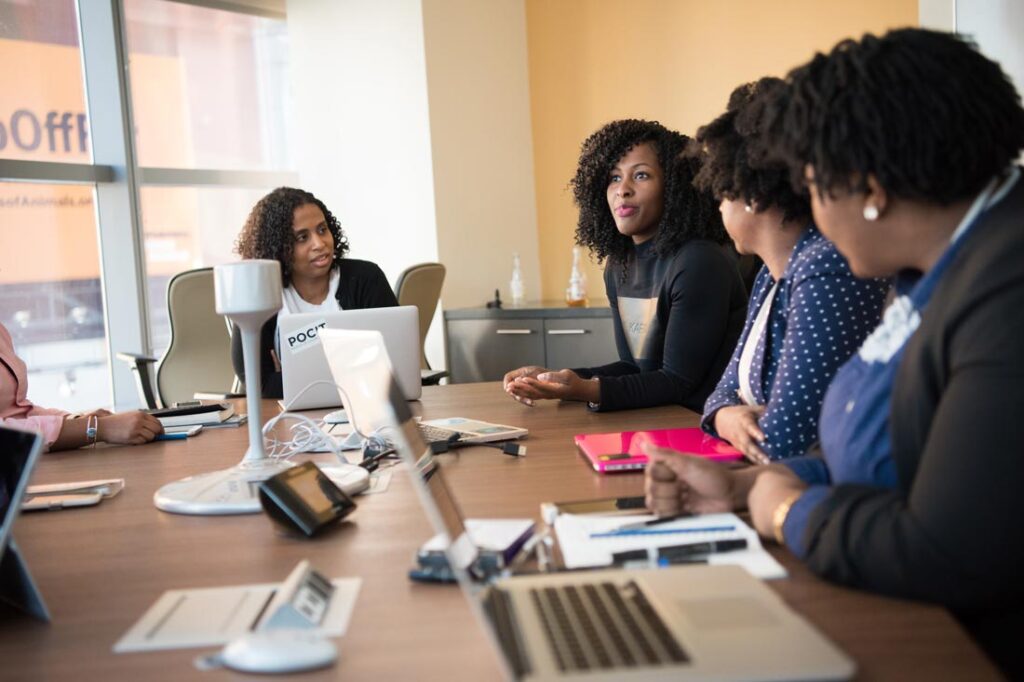 Employees sitting at a conference table listening to their boss speak, showing ways managers can create an environment where their team can thrive