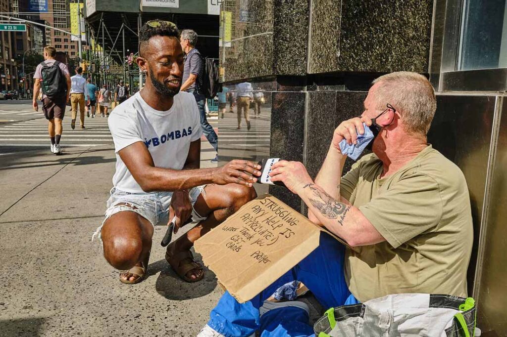 Bombas socks employee giving a pair of socks to an unhoused person because Bombas is one of the companies that give back to community