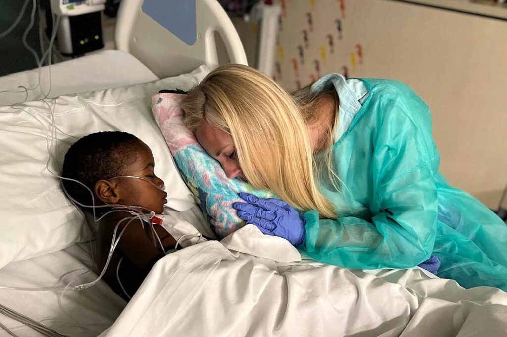 For You Haiti founder Alana Kaye comforting a young Haitian boy in a hospital bed