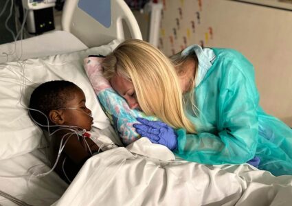 For You Haiti founder Alana Kaye comforting a young Haitian boy in a hospital bed