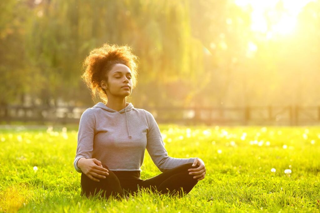 Woman practicing gratitude meditation outside on the grass