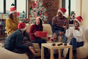 5 colleagues in Santa Claus hats exchanging Christmas gifts for coworkers