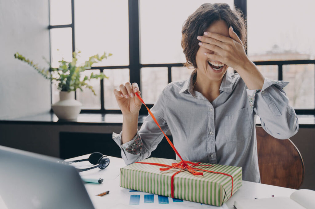 Excited woman covering her eyes and opening her Enneagram gift.