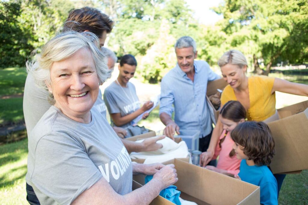 Mature woman smiling and holding a box because she knows places to volunteer