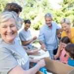 Mature woman smiling and holding a box because she knows places to volunteer