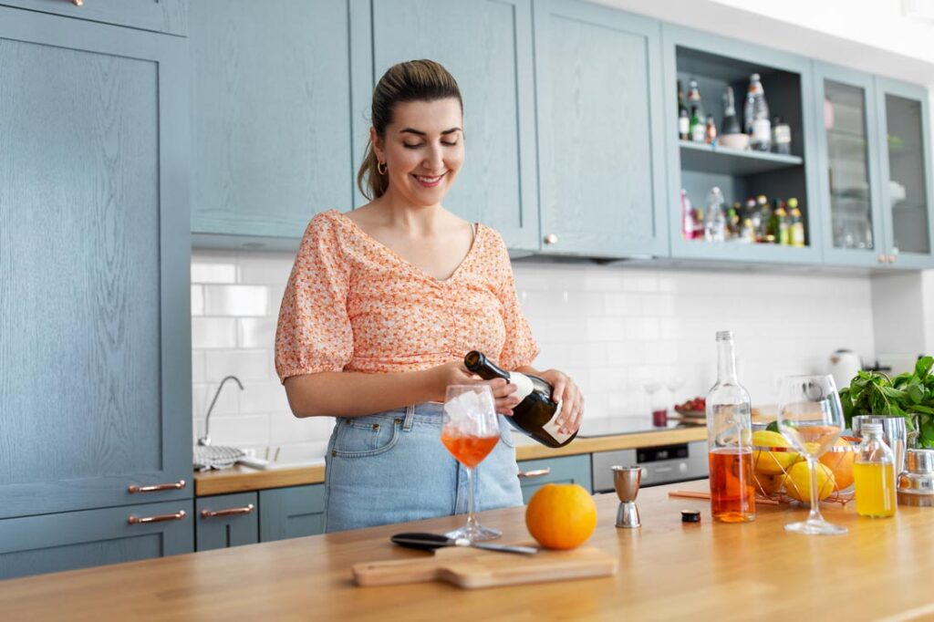 Woman in her kitchen smiling and mixing a mocktail because she has a nonalcoholic home bar