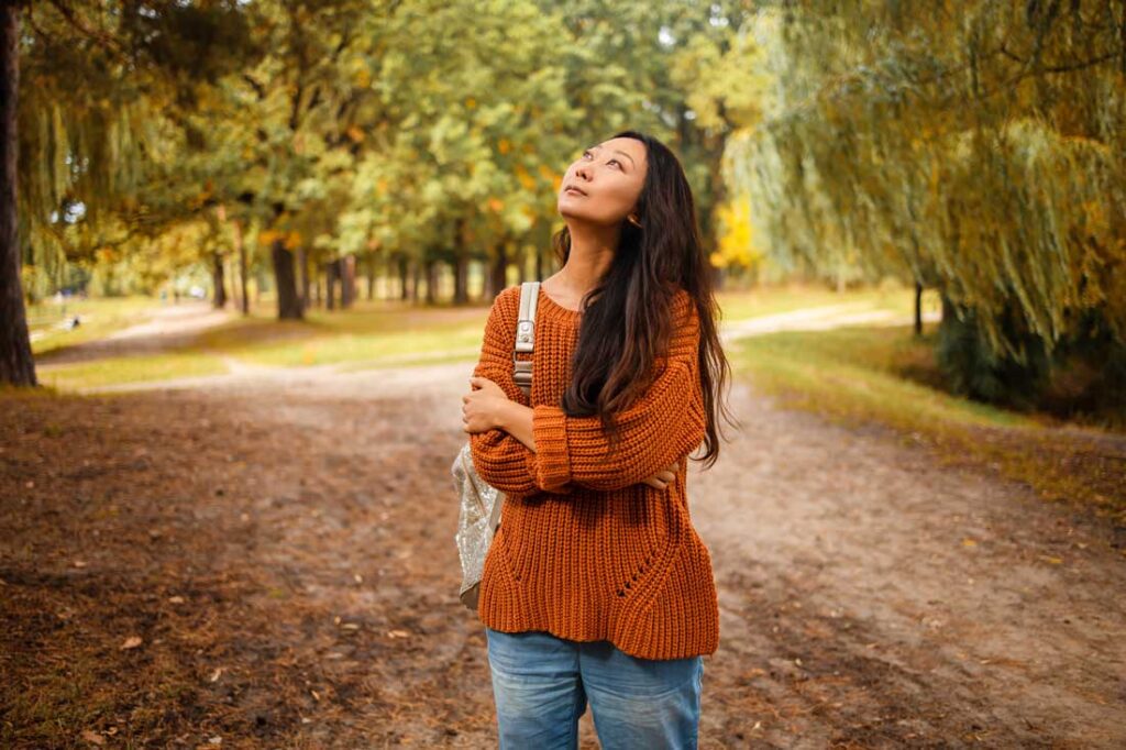 Asian woman looking up at the trees learning how to be more curious