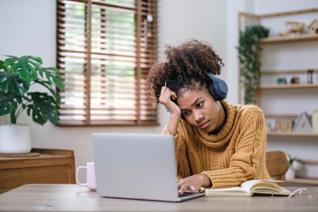 Young Black woman bored in front of her computer struggling with Zoom fatigue and looking for Zoom fatigue remedies