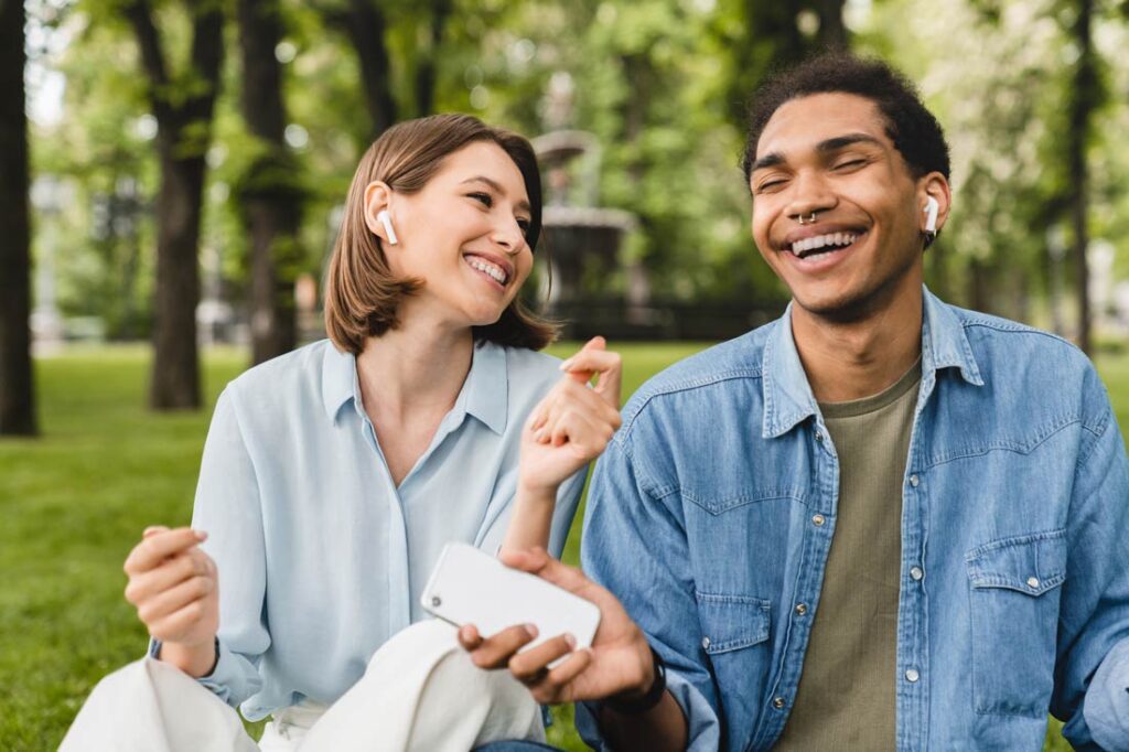 Couple listening to relationship podcasts together outside smiling