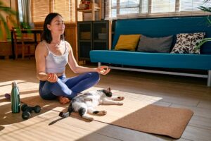 Woman practicing gratitude affirmations on her living room floor with her cat