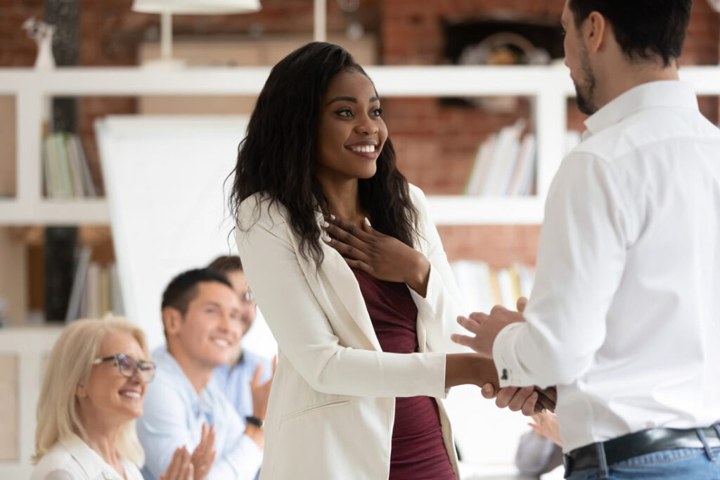 Woman shaking hand with her boss smiling humbly after learning how to get a promotion at work
