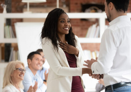 Woman shaking hand with her boss smiling humbly after learning how to get a promotion at work
