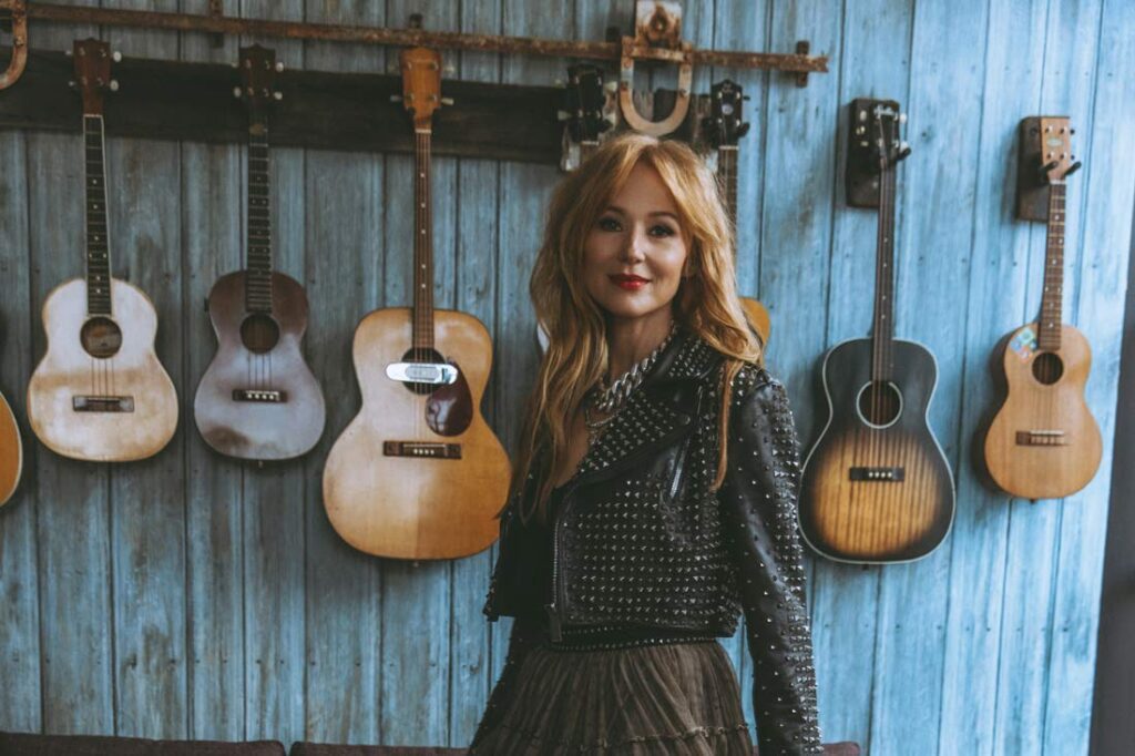 Singer songwriter Jewel standing in front of her guitars