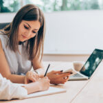 to business woman sitting at a desk writing goals